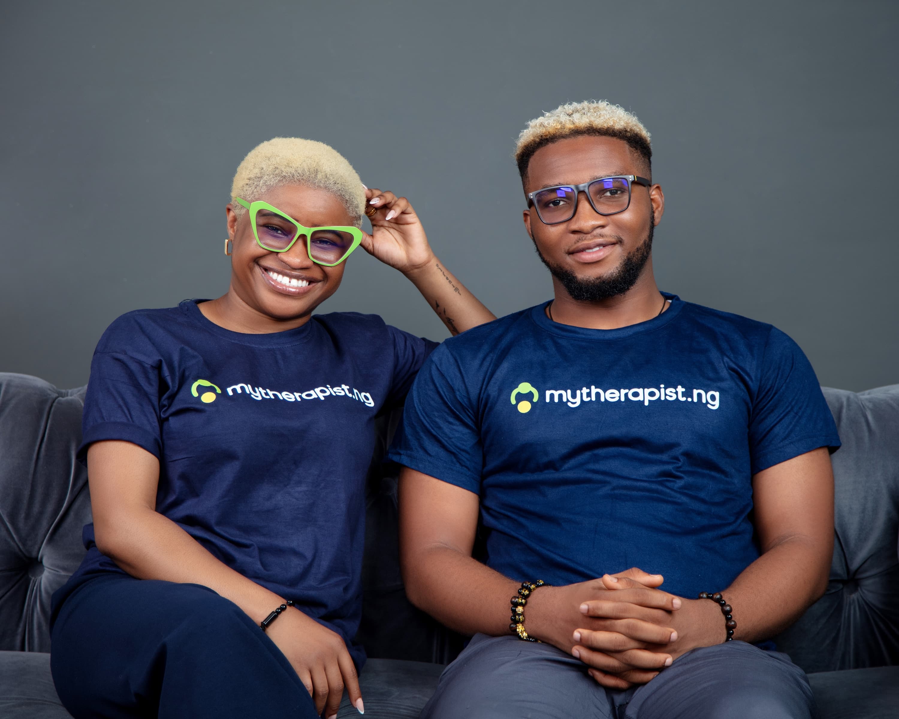 Dedoyin Ajayi and Oluwaseun Raphael Afolayan sitting on a sofa in Mytherapist.ng T-shirts