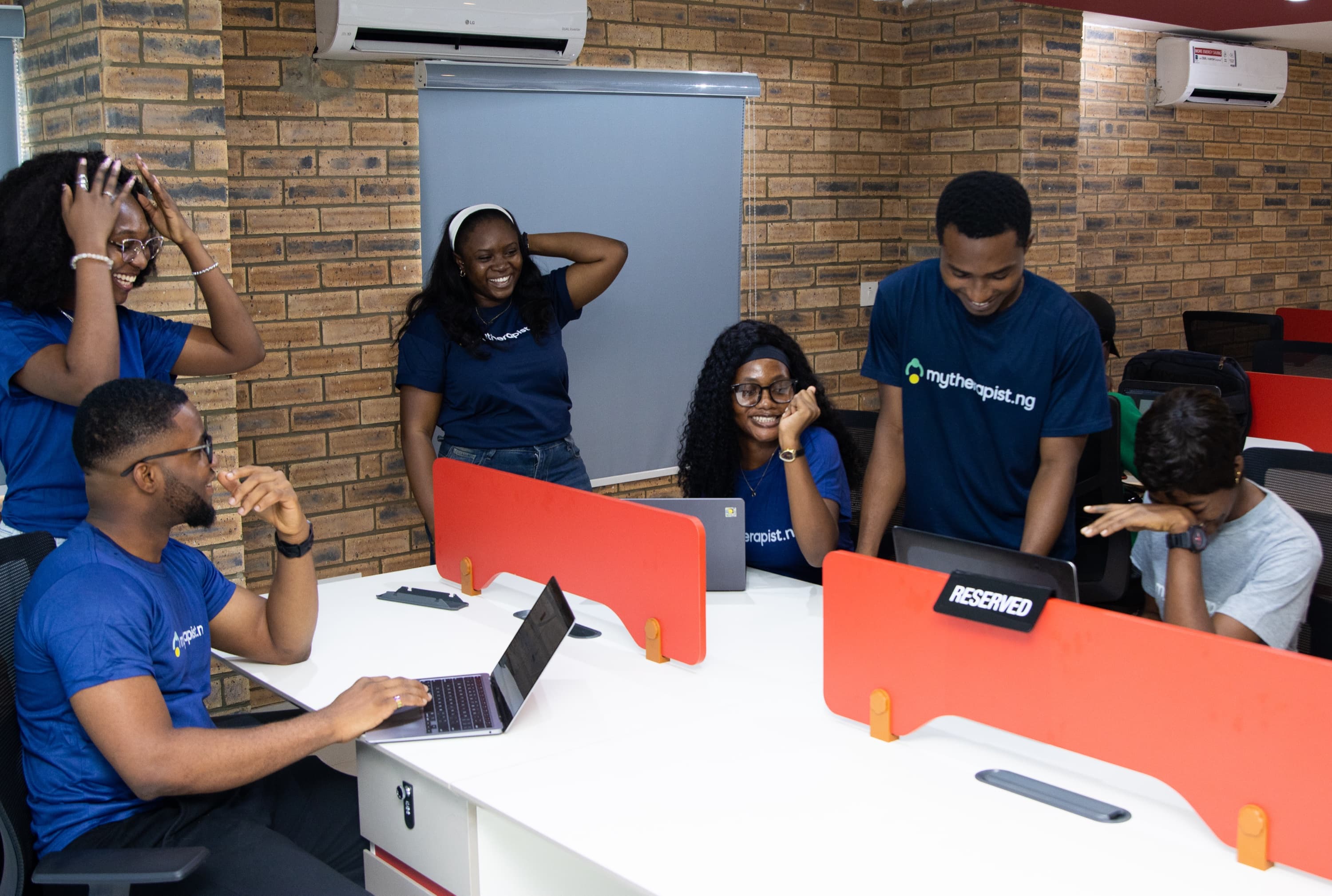 Mytherapist.ng team members laughing together around a row of desks in the office