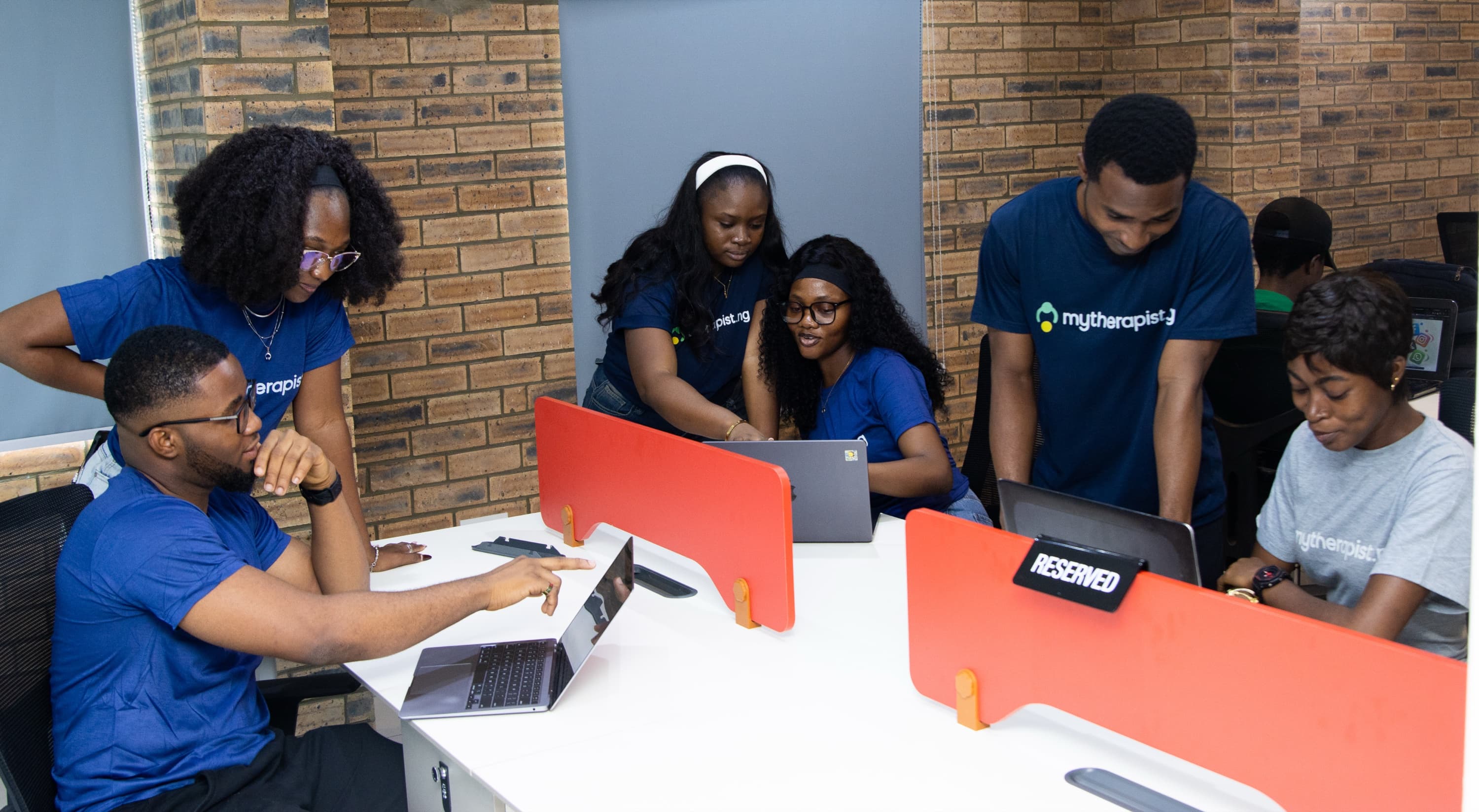 Mytherapist.ng team members working at laptops along a row of desks in the office