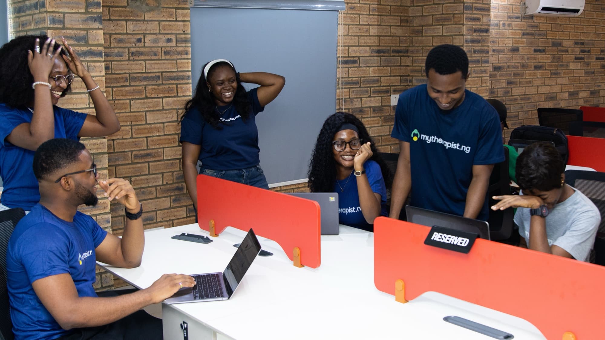 Mytherapist.ng team members laughing together around a row of desks in the office